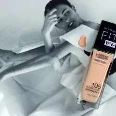 Maybelline Fit Me podkład rozświetlający w odcieniu 105 Natural Ivory na tle czarno-białej sesji zdjęciowej.
