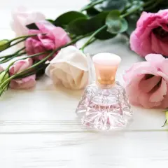 Elegancka buteleczka perfum wśród różowych kwiatów. Inspiracja, jak zrobić perfumy z płatków róż.