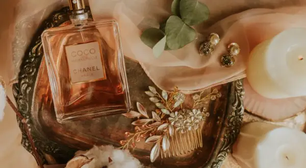 Flakon perfum Chanel Coco Mademoiselle, biżuteria i świece na ozdobnej tacy.