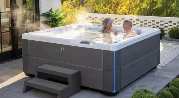 Para relaksu w ogrodzie: para cieszy się gorącą kąpielą w nowoczesnych wannach spa ogrodowych, otoczonych zielenią i słońcem.