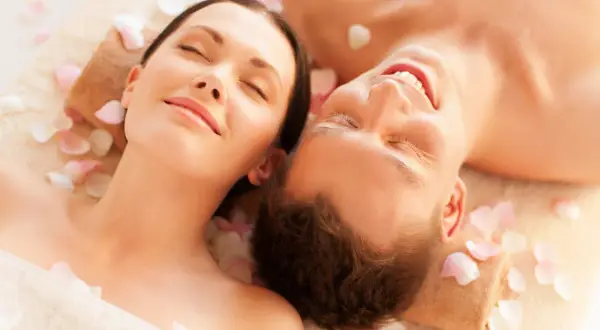 Para spędza relaksujący dzień w spa, leżąc wśród płatków róż.
