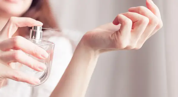 Kobieta rozpyla perfumy na nadgarstek. Zapach przypomina Niveę, otulając skórę delikatną mgiełką.