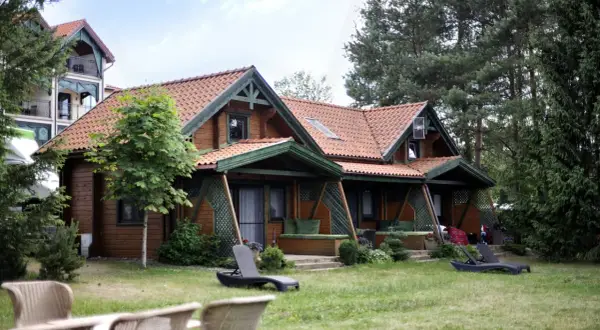 Drewniany domek spa na Mazurach, otoczony zielenią. Leżaki zapraszają do relaksu.